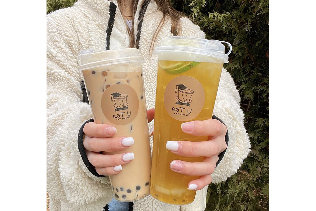 person holding two specialty drinks in clear cups