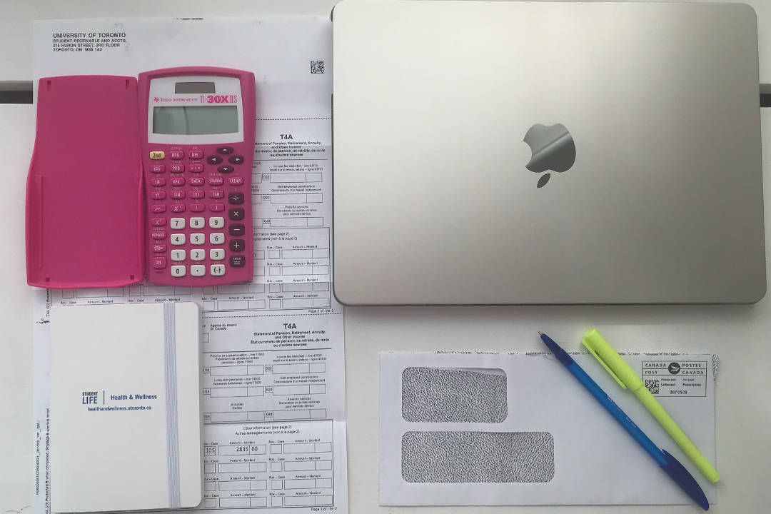 Laptop, calculator, T4 and T2022 slips laid out on desk.